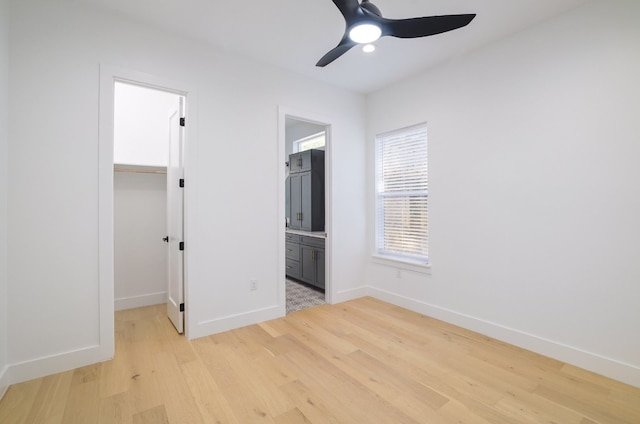 unfurnished bedroom with ceiling fan, a closet, a spacious closet, and light hardwood / wood-style flooring