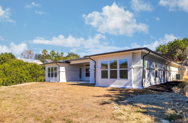 back of property with central air condition unit and a yard