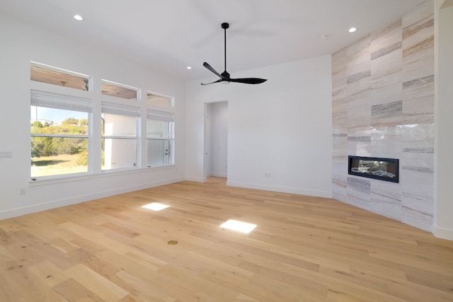 unfurnished living room featuring ceiling fan, light wood-type flooring, and a fireplace