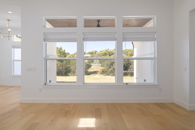 unfurnished room featuring a chandelier and light hardwood / wood-style flooring