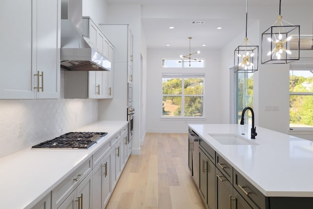 kitchen with a wealth of natural light, sink, wall chimney exhaust hood, and appliances with stainless steel finishes