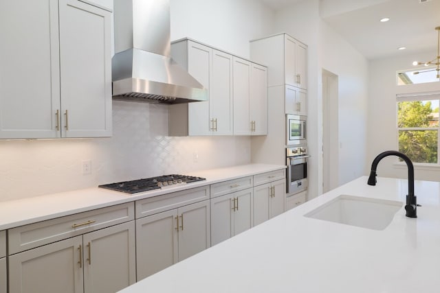 kitchen with decorative backsplash, appliances with stainless steel finishes, wall chimney exhaust hood, and sink