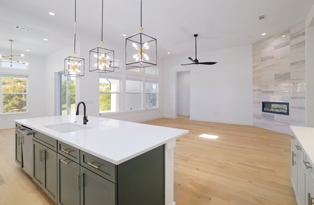 kitchen with a healthy amount of sunlight, a tile fireplace, sink, and a kitchen island with sink