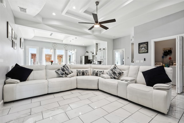 living room with ceiling fan and a tray ceiling