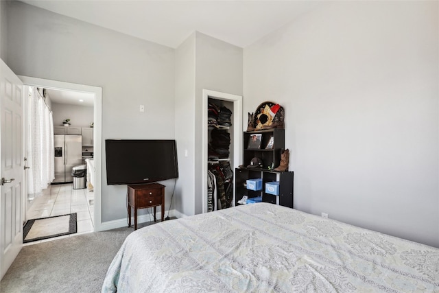 bedroom featuring stainless steel fridge, light colored carpet, and a closet