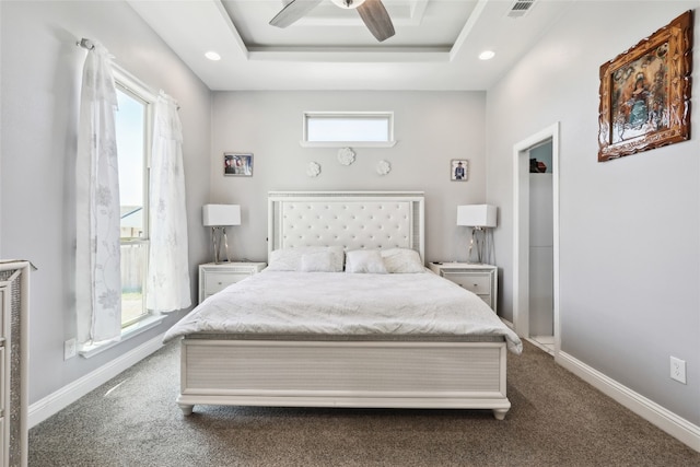 carpeted bedroom featuring a tray ceiling, multiple windows, and ceiling fan