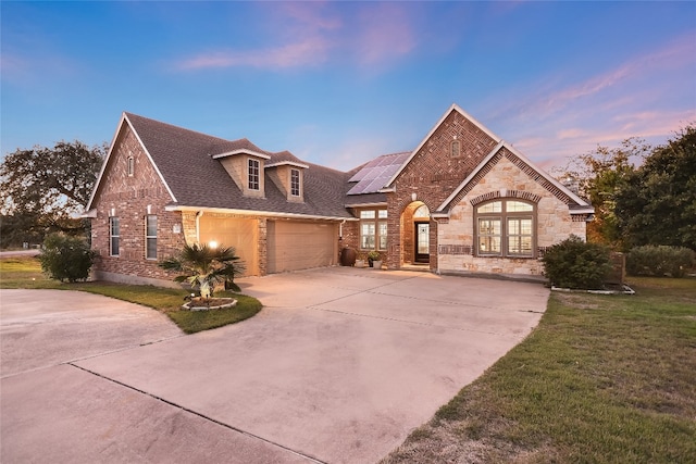 view of front of property with solar panels, a garage, and a lawn