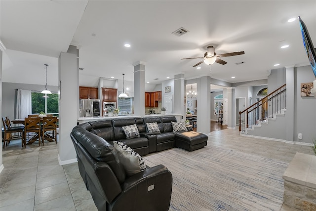 living room with ceiling fan with notable chandelier, light tile patterned floors, and decorative columns