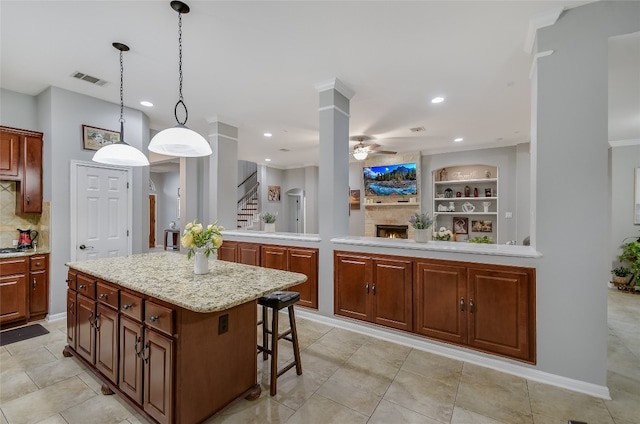 kitchen featuring built in shelves, a kitchen breakfast bar, backsplash, pendant lighting, and a kitchen island