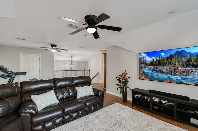 living room with ceiling fan with notable chandelier and dark hardwood / wood-style floors