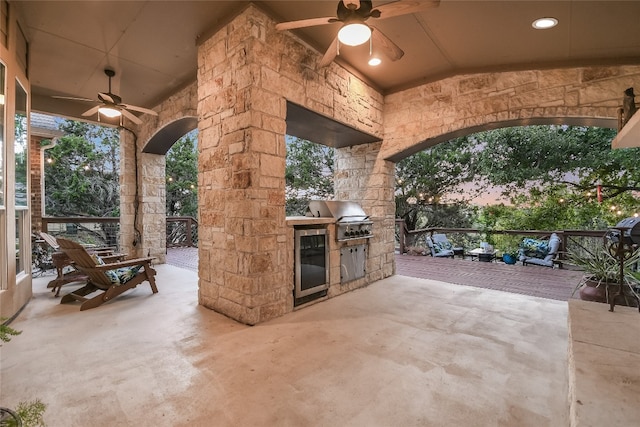 patio terrace at dusk featuring ceiling fan and area for grilling