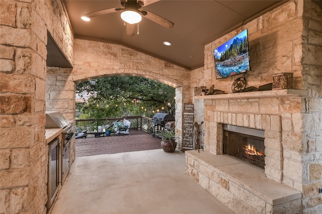 view of patio / terrace featuring an outdoor stone fireplace, area for grilling, ceiling fan, and a grill