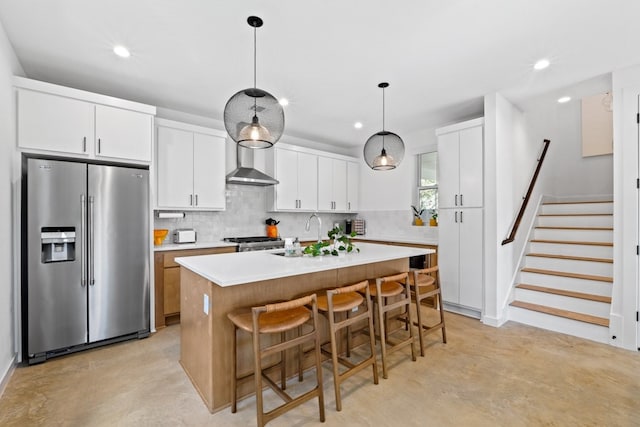 kitchen featuring pendant lighting, decorative backsplash, an island with sink, appliances with stainless steel finishes, and white cabinetry