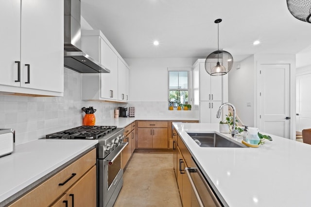 kitchen featuring appliances with stainless steel finishes, wall chimney exhaust hood, sink, pendant lighting, and white cabinets