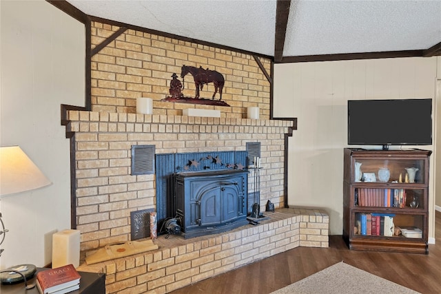 living room with hardwood / wood-style flooring, a wood stove, beamed ceiling, and a textured ceiling