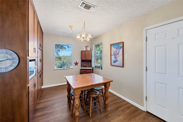 dining area with a textured ceiling, dark wood-type flooring, and a chandelier