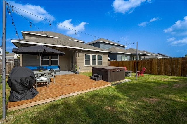 rear view of house featuring a lawn, a hot tub, and a deck