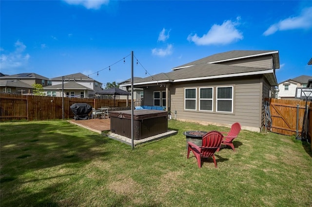 rear view of property featuring a yard and a hot tub