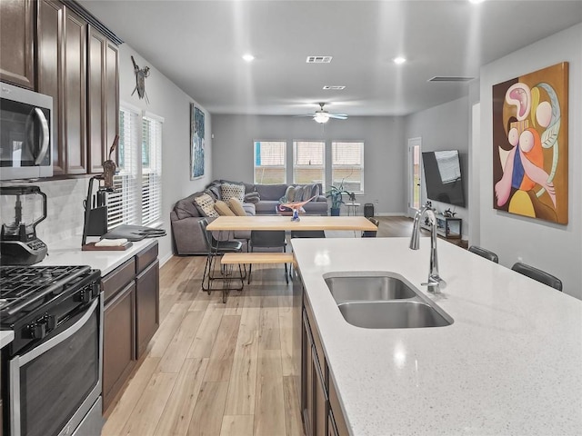 11303 Copper Spring Dr Unit 87, Austin, TX 78748 - kitchen with stainless steel appliances, open floor plan, dark brown cabinetry, light wood-style floors, and a ceiling fan