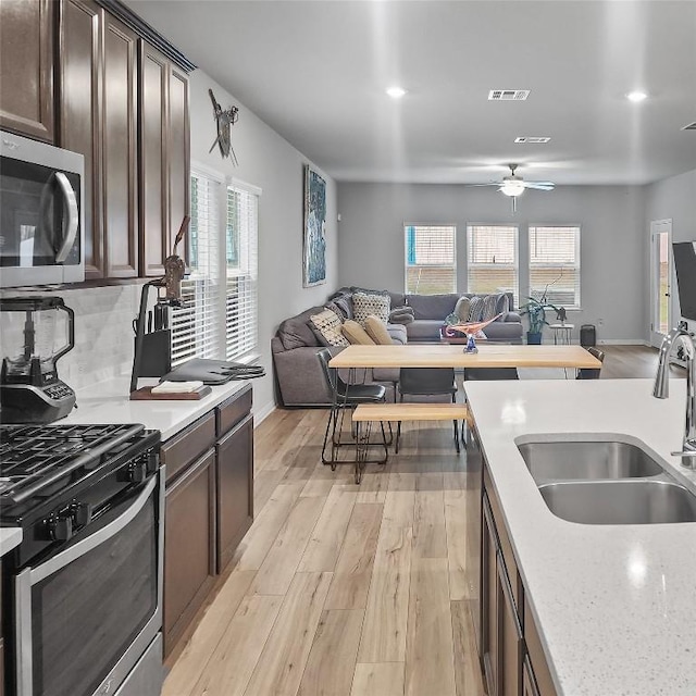 11303 Copper Spring Dr Unit 87, Austin, TX 78748 - kitchen featuring stainless steel appliances, open floor plan, dark brown cabinetry, ceiling fan, and light wood-style flooring