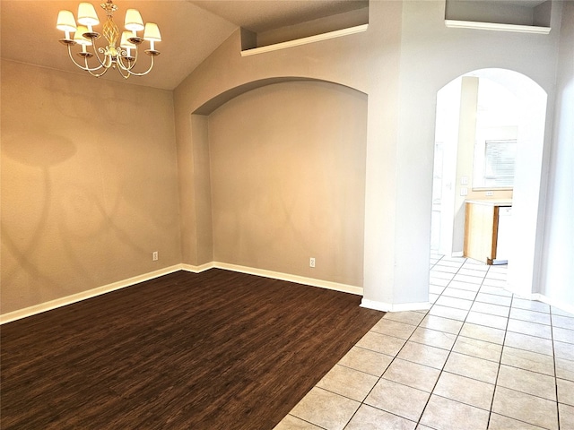 spare room featuring a chandelier, lofted ceiling, and light wood-type flooring