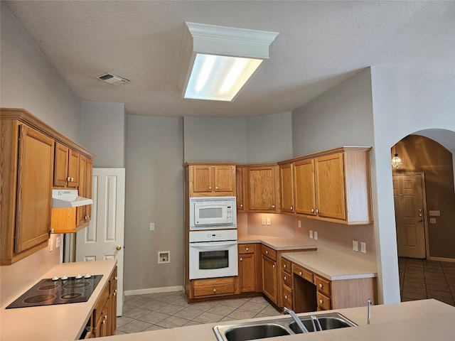 kitchen with a textured ceiling, sink, light tile patterned floors, and white appliances