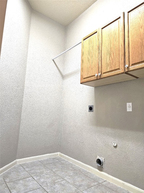 washroom with electric dryer hookup, gas dryer hookup, light tile patterned flooring, and cabinets