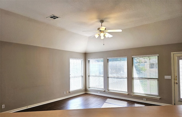 empty room with a textured ceiling, ceiling fan, wood-type flooring, and lofted ceiling