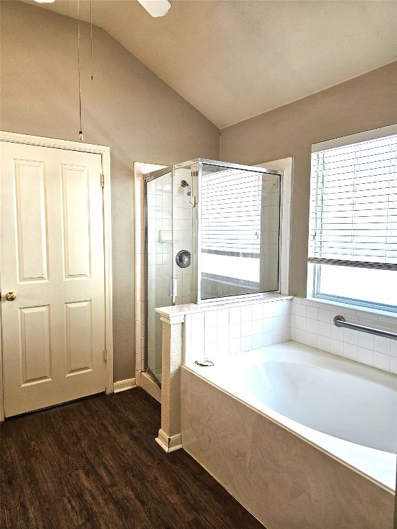 bathroom featuring shower with separate bathtub, hardwood / wood-style flooring, and vaulted ceiling