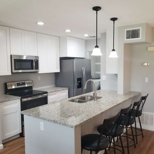 kitchen featuring white cabinetry, sink, a kitchen breakfast bar, dark hardwood / wood-style flooring, and appliances with stainless steel finishes