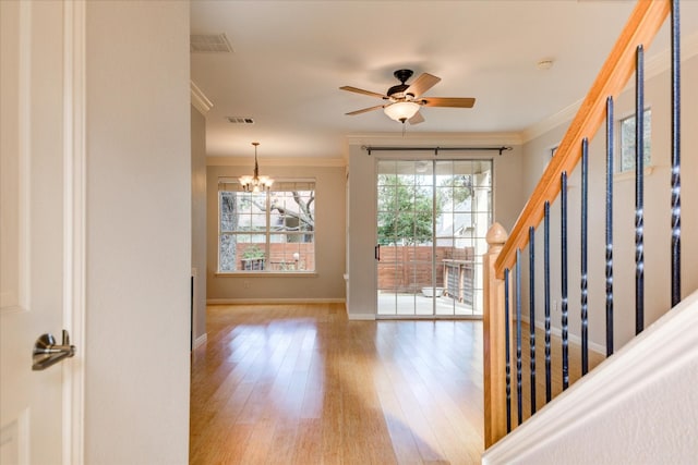 foyer entrance with ceiling fan with notable chandelier, wood-type flooring, and ornamental molding