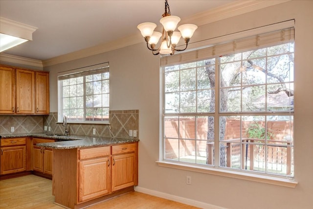 11000 Anderson Mill Rd Unit 9, Austin, TX 78750 - kitchen featuring crown molding, a chandelier, light wood-type flooring, backsplash, and dark stone countertops