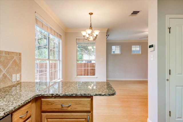 kitchen with a notable chandelier, light stone countertops, crown molding, and light hardwood / wood-style flooring