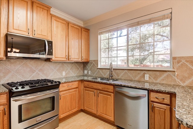 kitchen with sink, stainless steel appliances, light stone counters, crown molding, and light wood-type flooring