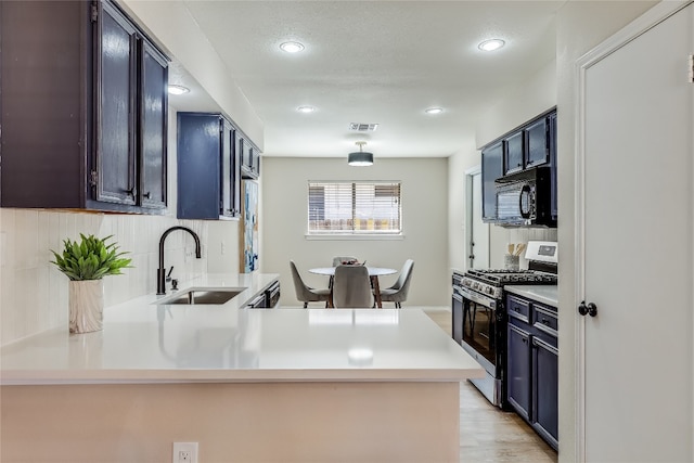 kitchen featuring sink, light hardwood / wood-style flooring, a textured ceiling, kitchen peninsula, and stainless steel range with gas stovetop