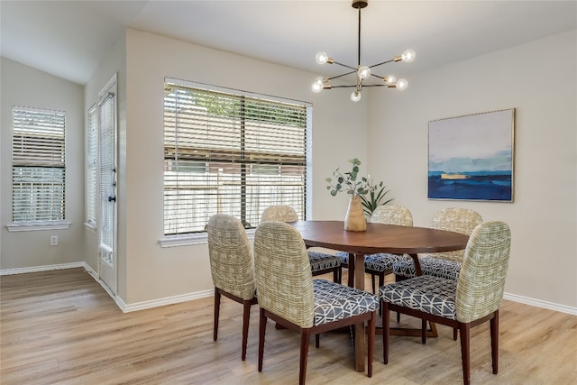 dining area with light hardwood / wood-style floors, lofted ceiling, and an inviting chandelier