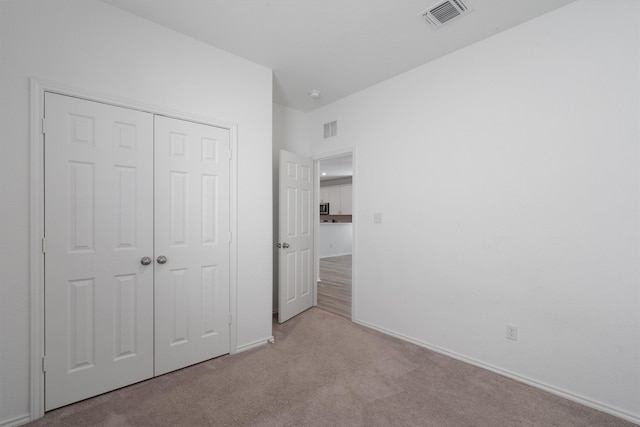 unfurnished bedroom with a closet and light colored carpet