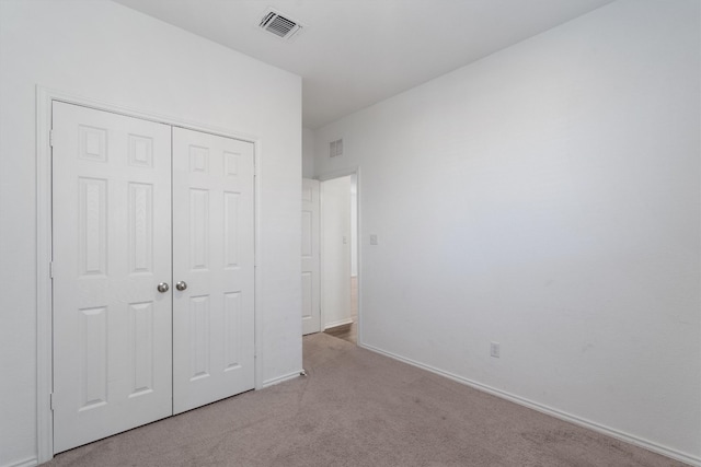 unfurnished bedroom featuring light carpet and a closet