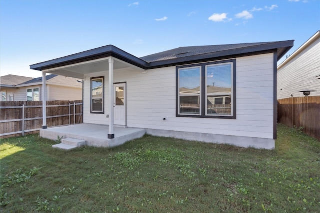 back of house with a patio and a lawn