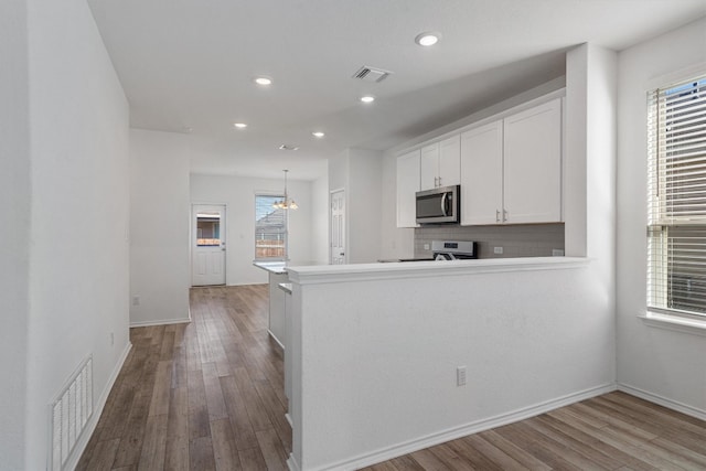 kitchen featuring white stove, wood-type flooring, white cabinetry, and kitchen peninsula