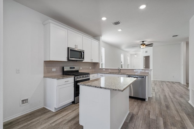 kitchen featuring white cabinets, a kitchen island, stainless steel appliances, and light hardwood / wood-style flooring