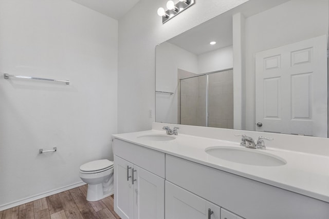 bathroom featuring hardwood / wood-style floors, vanity, toilet, and a shower with shower door