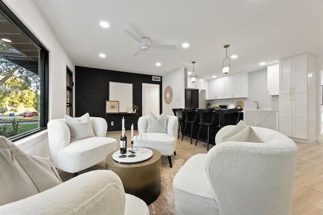 living room with light hardwood / wood-style flooring, ceiling fan, and sink