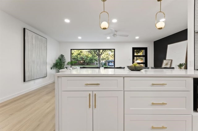 kitchen featuring light wood-type flooring, white cabinetry, and hanging light fixtures