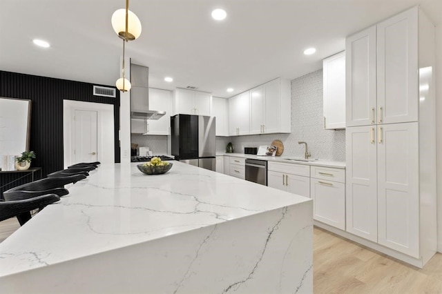 kitchen featuring sink, hanging light fixtures, light stone counters, white cabinets, and appliances with stainless steel finishes