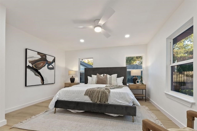 bedroom with ceiling fan, light hardwood / wood-style floors, and multiple windows