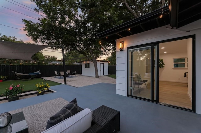 patio terrace at dusk with an outdoor living space, a storage unit, and a trampoline