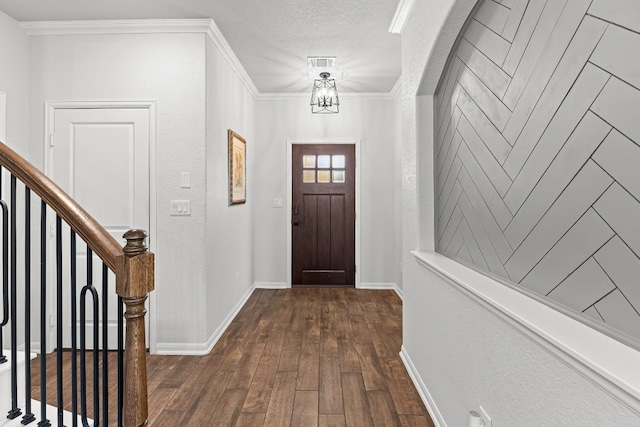 entryway featuring a chandelier, crown molding, dark wood-type flooring, and a textured ceiling