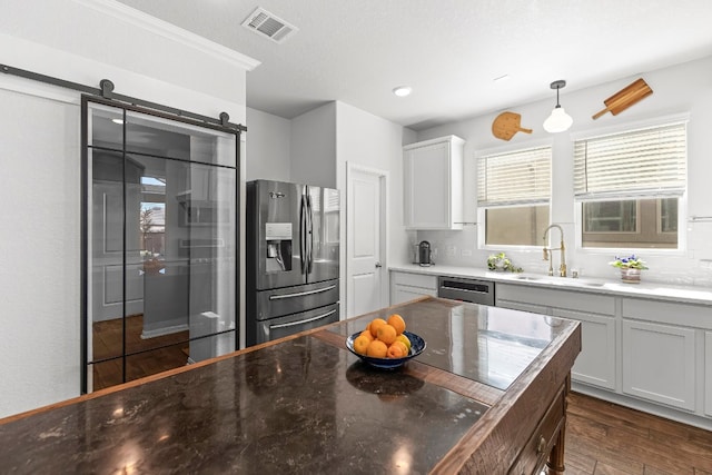 kitchen featuring pendant lighting, sink, a barn door, dark hardwood / wood-style flooring, and stainless steel appliances