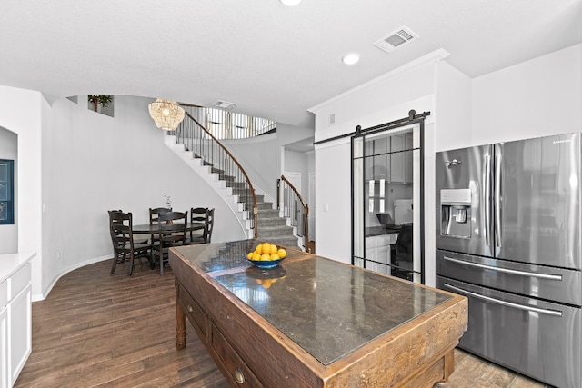 kitchen with white cabinetry, dark wood-type flooring, a barn door, stainless steel refrigerator with ice dispenser, and a chandelier